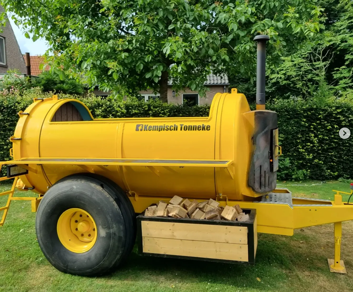 Dampende houtgestookte hottub van een omgebouwde giertank in een tuin bij avondlicht